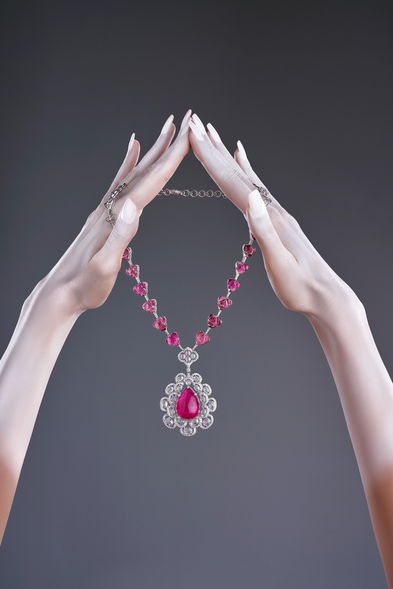 Ruby and diamond pendant necklace held between hands